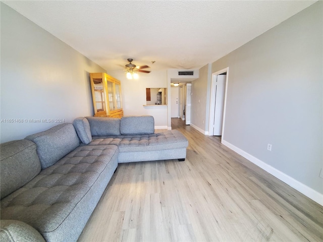 living room featuring ceiling fan, light hardwood / wood-style floors, and a textured ceiling