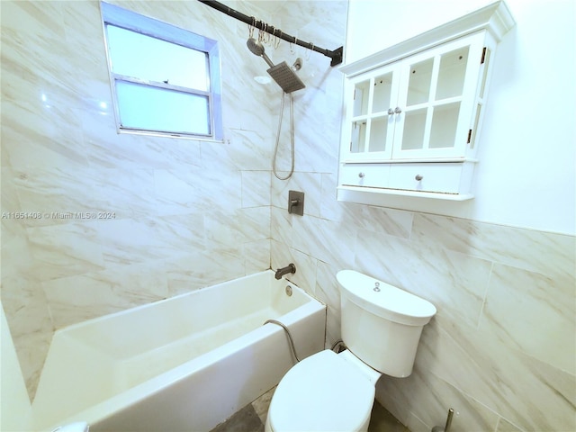 bathroom with tile walls, toilet, and tiled shower / bath