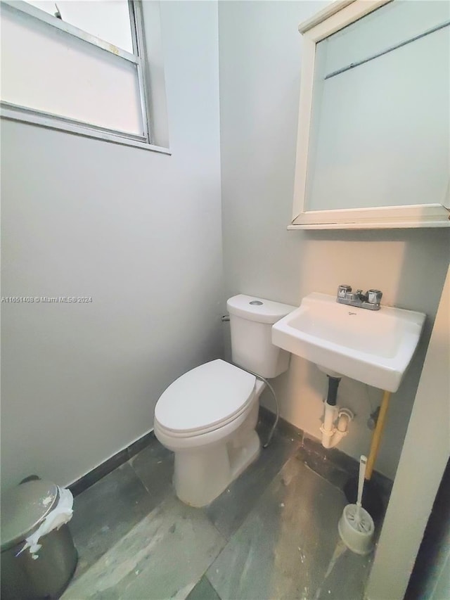 bathroom featuring concrete flooring, toilet, and sink