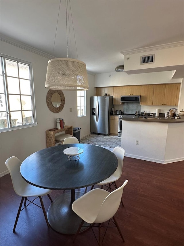 dining space featuring ornamental molding, dark wood-type flooring, and sink