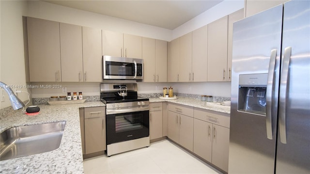 kitchen with gray cabinets, light tile patterned floors, light stone counters, sink, and appliances with stainless steel finishes