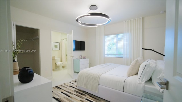 bedroom with connected bathroom and light wood-type flooring