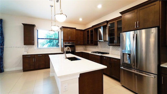 kitchen with appliances with stainless steel finishes, tasteful backsplash, an island with sink, sink, and wall chimney range hood