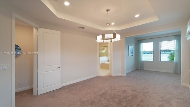 carpeted spare room featuring a tray ceiling