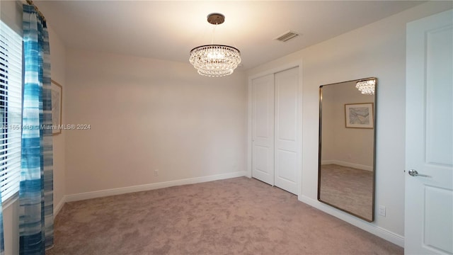 unfurnished bedroom with light colored carpet, a notable chandelier, and a closet