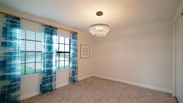 carpeted empty room featuring a notable chandelier