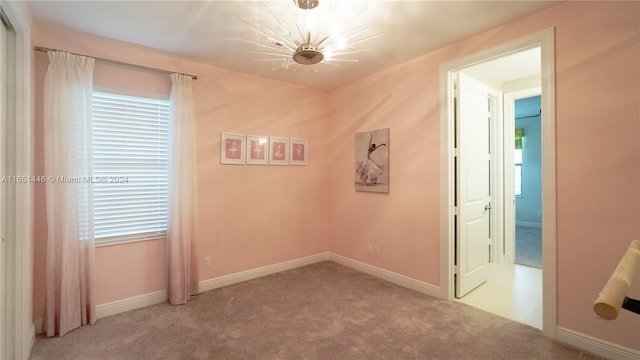 empty room featuring an inviting chandelier and light colored carpet