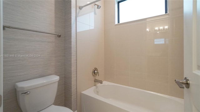 bathroom with tiled shower / bath combo, tile walls, and toilet