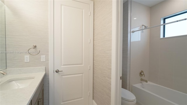 full bathroom with tile walls, toilet, tiled shower / bath combo, and vanity