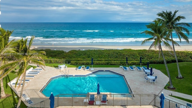 view of pool with a beach view, a water view, and a patio area