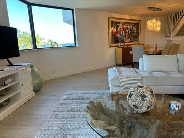 living area with a chandelier, light wood-type flooring, and baseboards