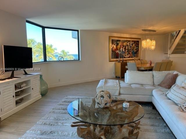 living area featuring baseboards, light wood-type flooring, and an inviting chandelier