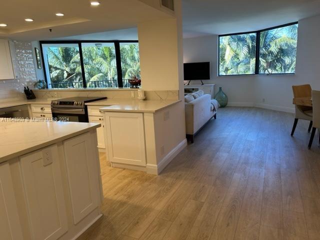 kitchen featuring electric stove, light wood-type flooring, light countertops, and white cabinets