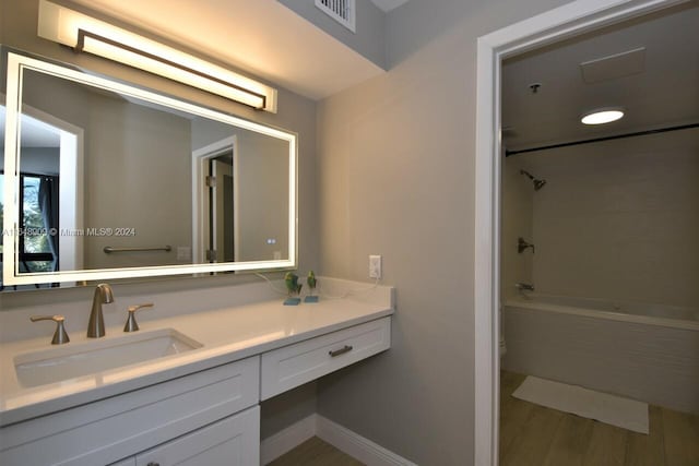 bathroom featuring toilet, wood finished floors, vanity, visible vents, and tub / shower combination