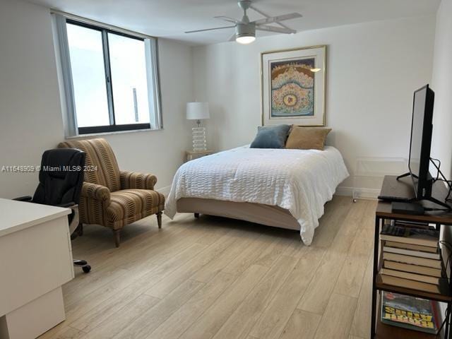 bedroom with light wood-style flooring, baseboards, and ceiling fan