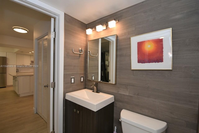 bathroom with vanity, toilet, tile walls, and hardwood / wood-style flooring