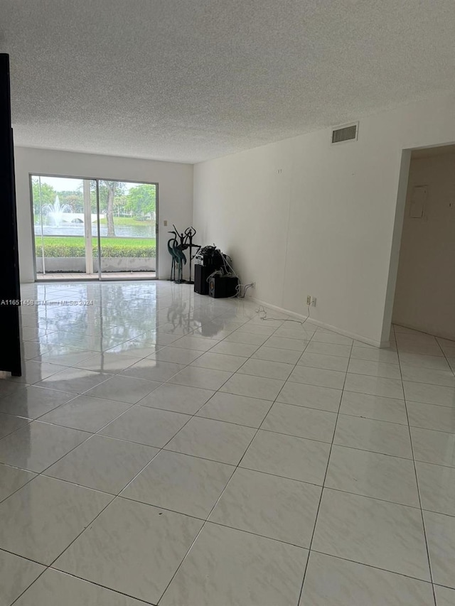 tiled empty room with a textured ceiling