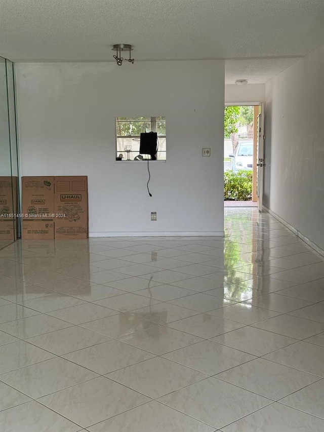 unfurnished room featuring a textured ceiling and light tile patterned floors