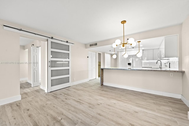 2625 Collins Ave Unit 309, Miami Beach, FL 33140 - unfurnished living room with baseboards, an inviting chandelier, a barn door, light wood-style floors, and visible vents