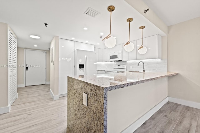 kitchen with white cabinets, white appliances, light wood-type flooring, and decorative light fixtures