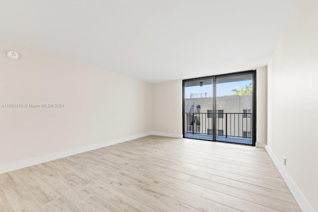 spare room with expansive windows and light hardwood / wood-style flooring