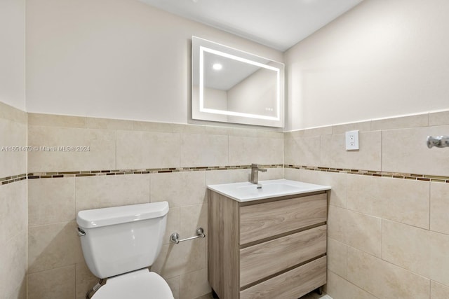 bathroom with tile walls, vaulted ceiling, vanity, and toilet