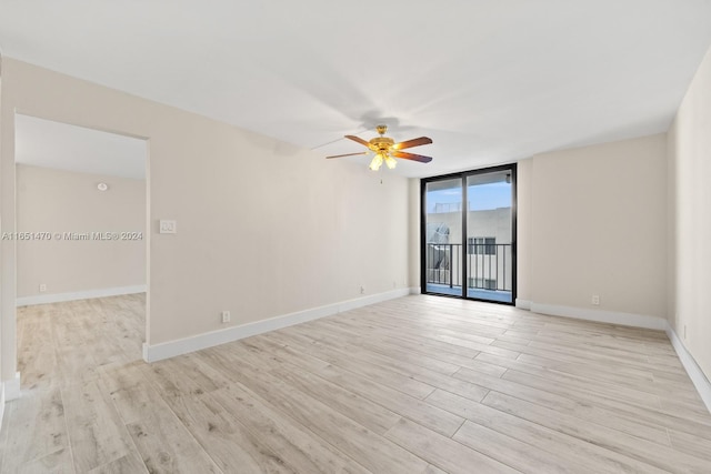 empty room with ceiling fan, floor to ceiling windows, and light hardwood / wood-style floors