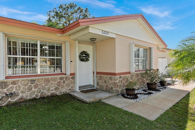 view of exterior entry with a lawn