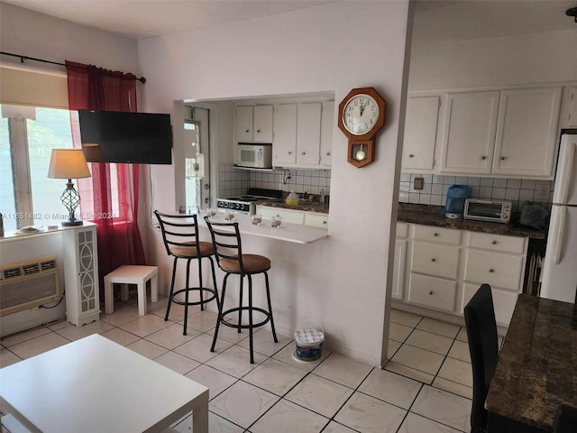 kitchen featuring white appliances, light tile patterned flooring, white cabinets, and tasteful backsplash