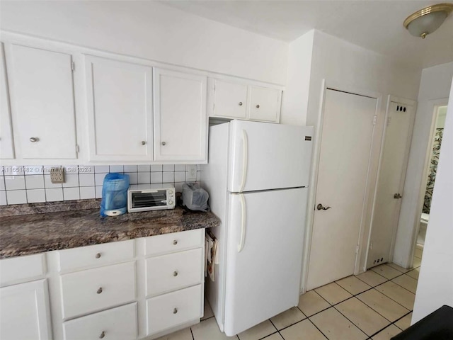 kitchen with white cabinetry, tasteful backsplash, light tile patterned flooring, and white fridge