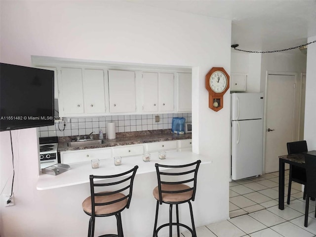 kitchen with backsplash, light tile patterned floors, white refrigerator, white cabinetry, and sink