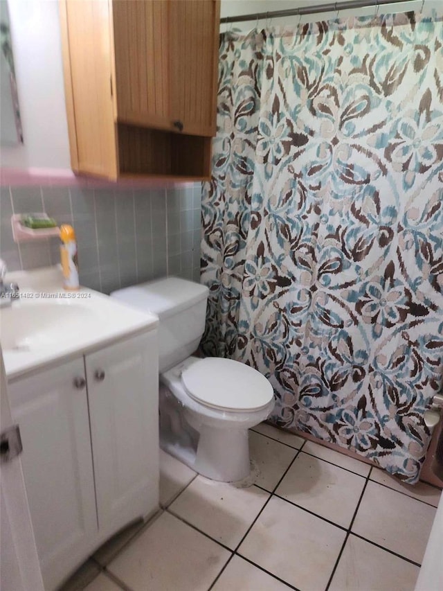 bathroom featuring tile patterned flooring, tile walls, toilet, and vanity