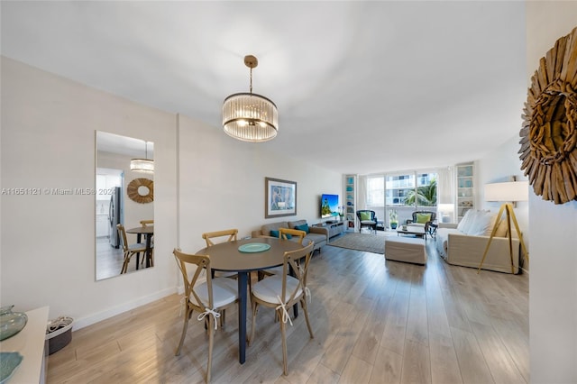 dining area with light wood-type flooring and a chandelier