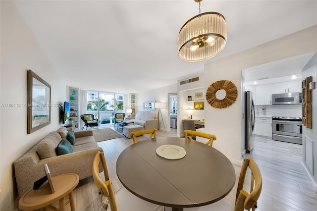 dining space featuring light wood-type flooring and an inviting chandelier