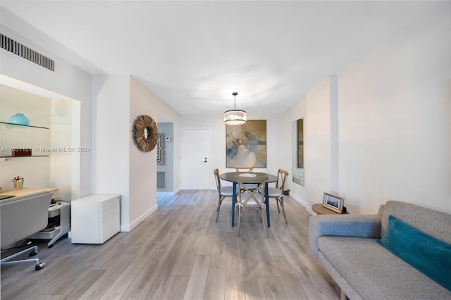 dining space featuring light hardwood / wood-style floors and a notable chandelier