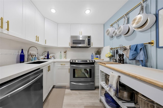 kitchen with light wood-type flooring, sink, appliances with stainless steel finishes, and white cabinets