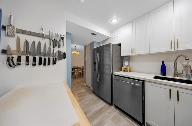 kitchen with white cabinets, appliances with stainless steel finishes, light hardwood / wood-style floors, and sink