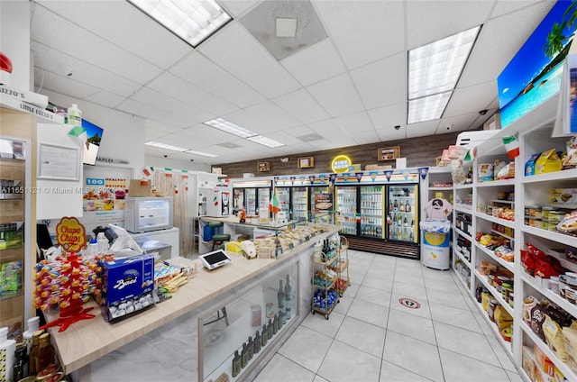 interior space with a paneled ceiling and light tile patterned flooring