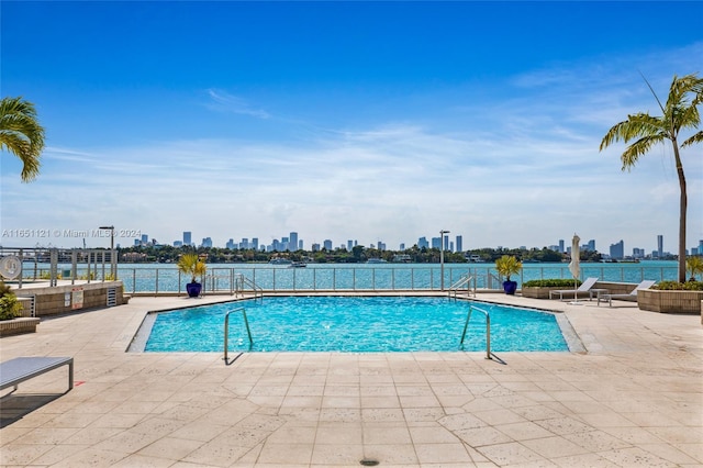 view of swimming pool with a water view and a patio