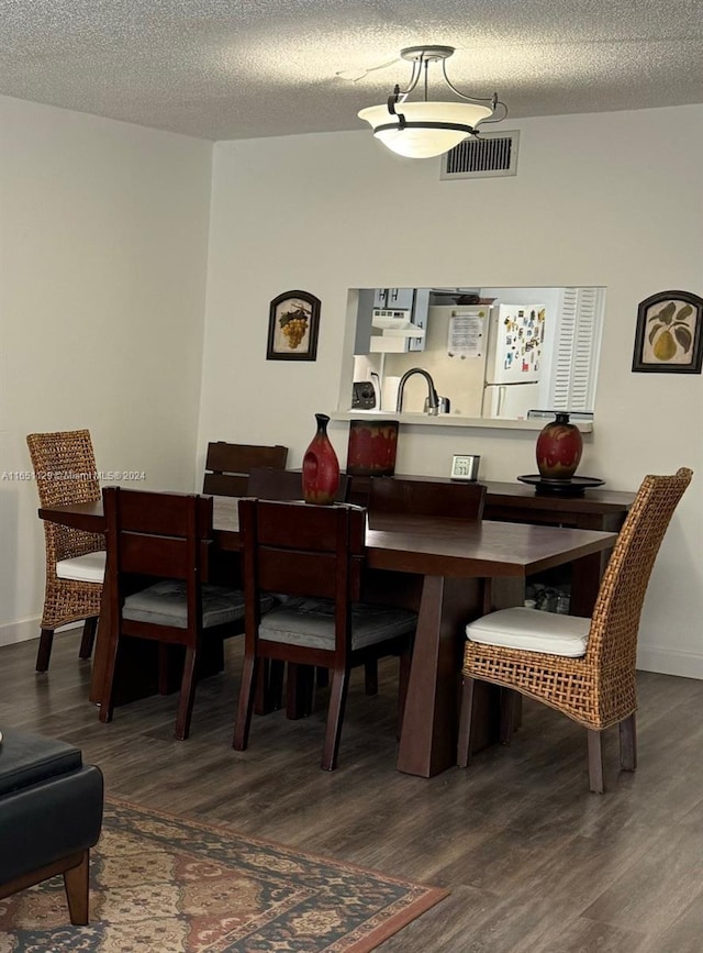 dining space featuring a textured ceiling and dark hardwood / wood-style floors