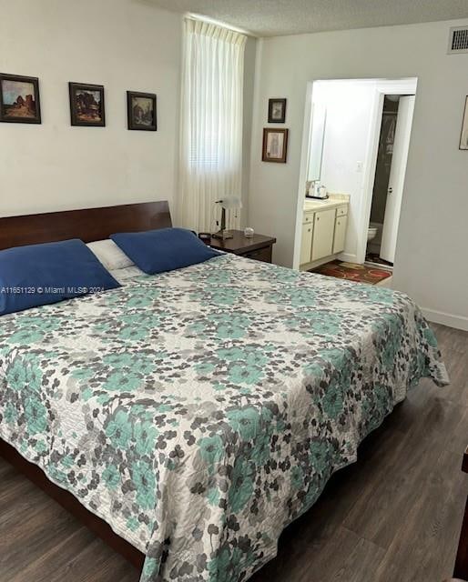 bedroom with dark wood-type flooring, connected bathroom, and a textured ceiling