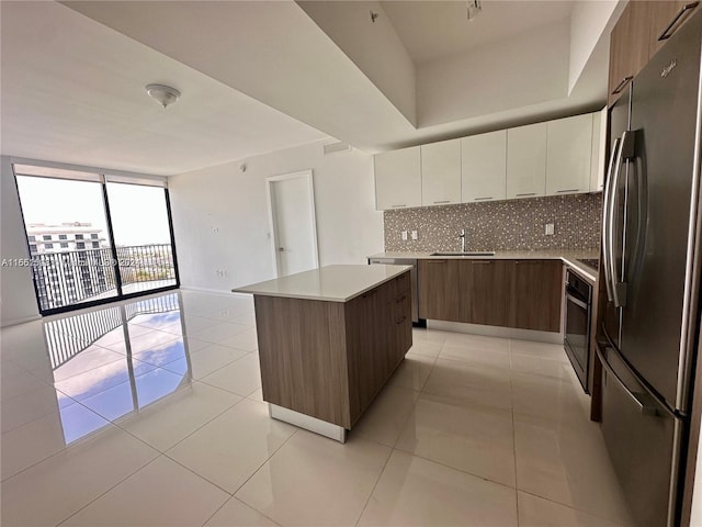 kitchen featuring light tile patterned floors, tasteful backsplash, a kitchen island, and stainless steel refrigerator