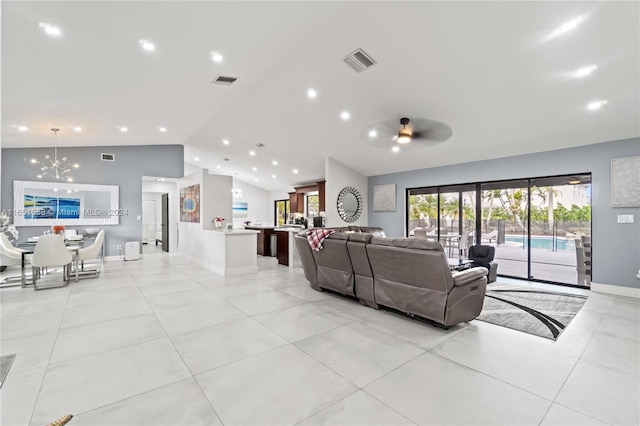 living room featuring ceiling fan with notable chandelier, light tile patterned flooring, and vaulted ceiling