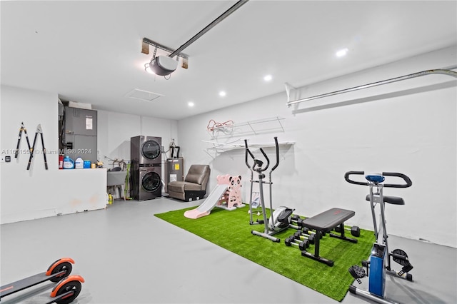 workout area with heating unit, concrete floors, stacked washer / dryer, and water heater