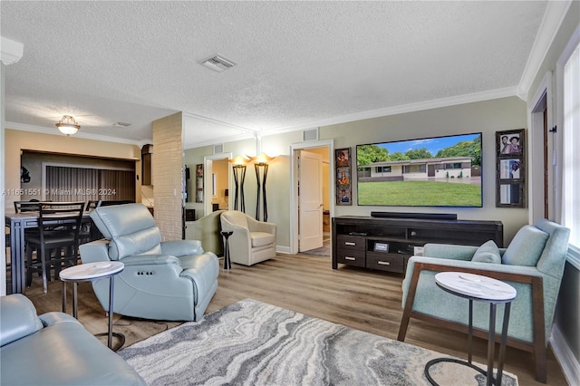 living room with ornamental molding, a textured ceiling, and hardwood / wood-style floors