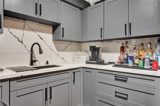 kitchen featuring gray cabinetry, sink, and backsplash