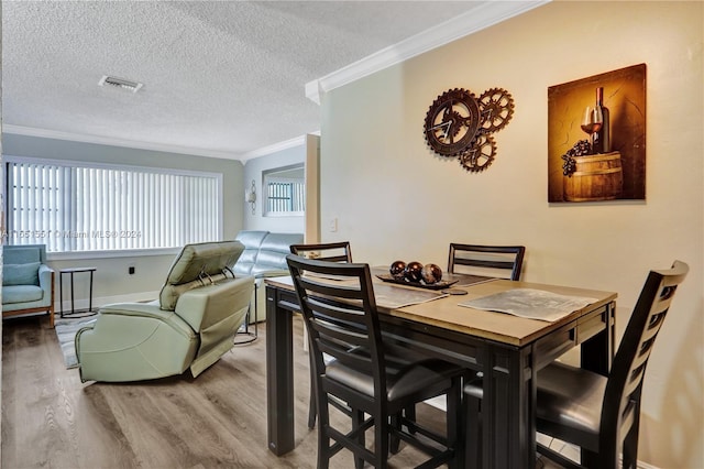 dining room featuring wood-type flooring, crown molding, and a textured ceiling