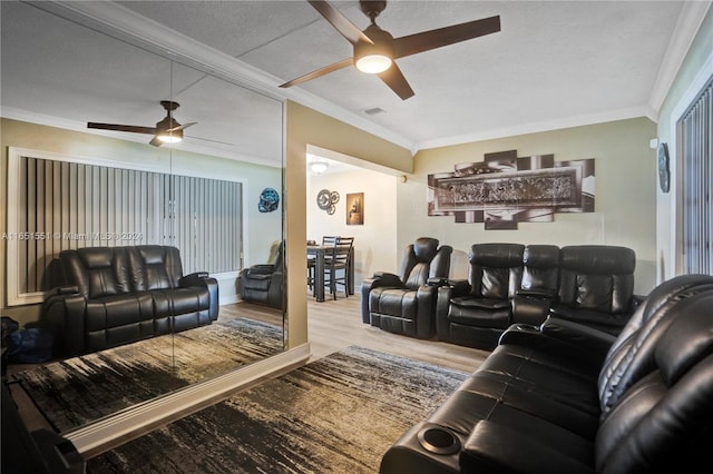 living room with light wood-type flooring, ceiling fan, a textured ceiling, and ornamental molding