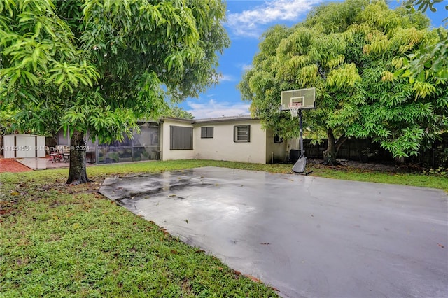 rear view of house with a lawn, a patio area, and basketball hoop