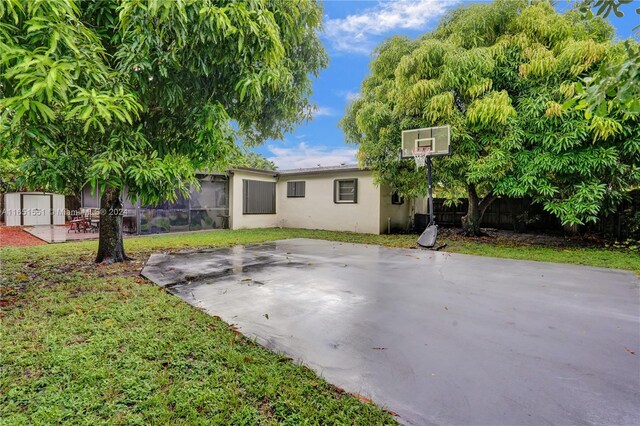 770 NW 175th Dr, Miami Gardens, FL 33169 - rear view of property featuring basketball hoop, fence, a lawn, and stucco siding